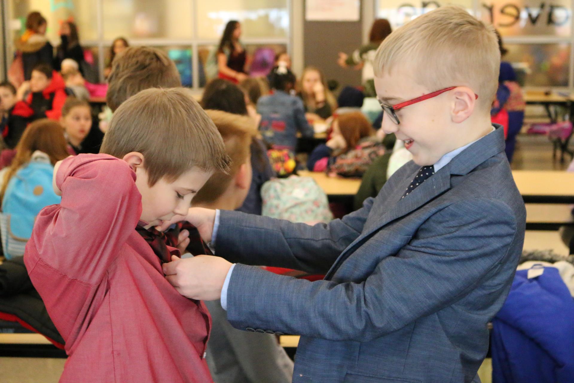 Student helps another student tie a tie.