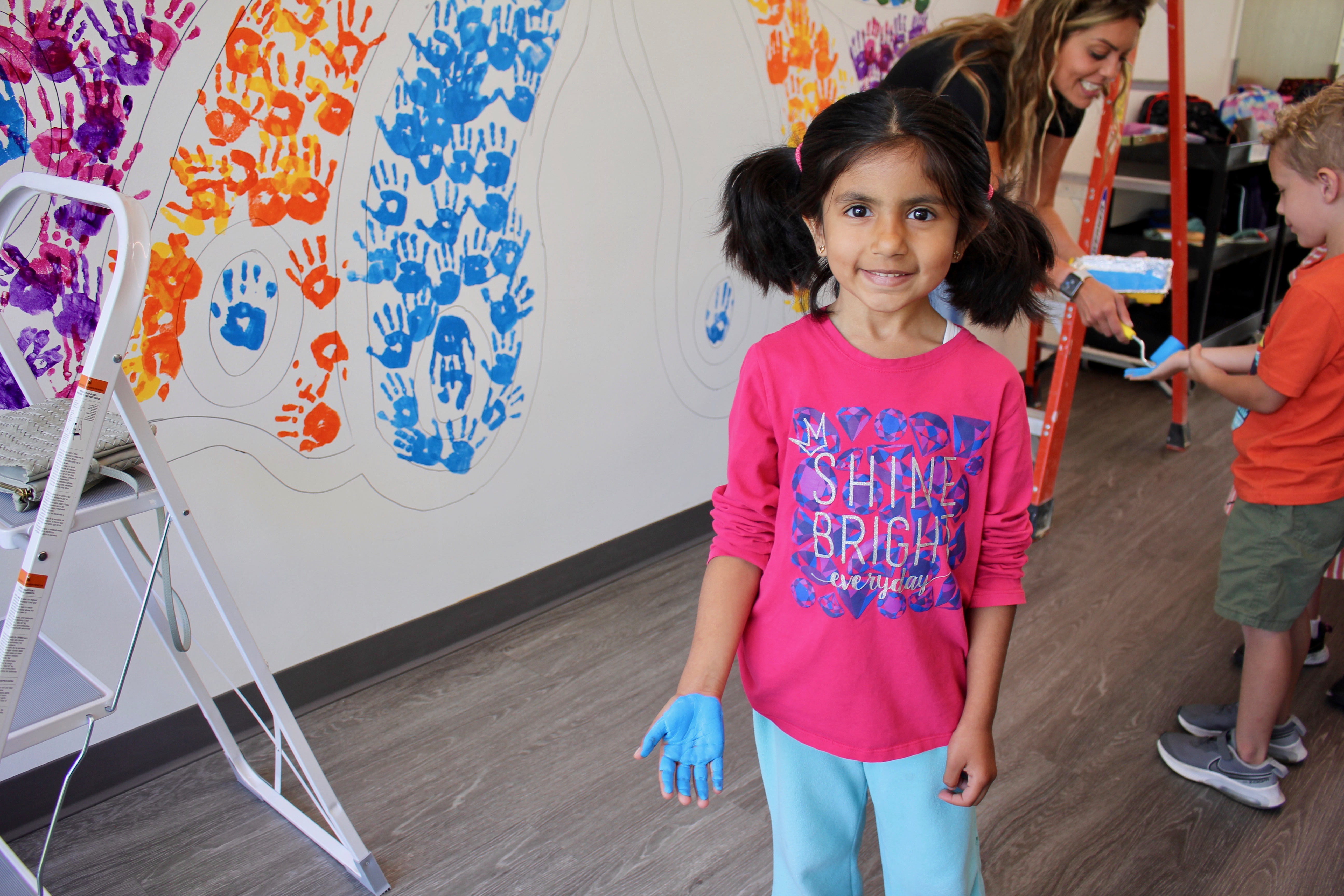 A student posing in front of the mural after placing a handprint