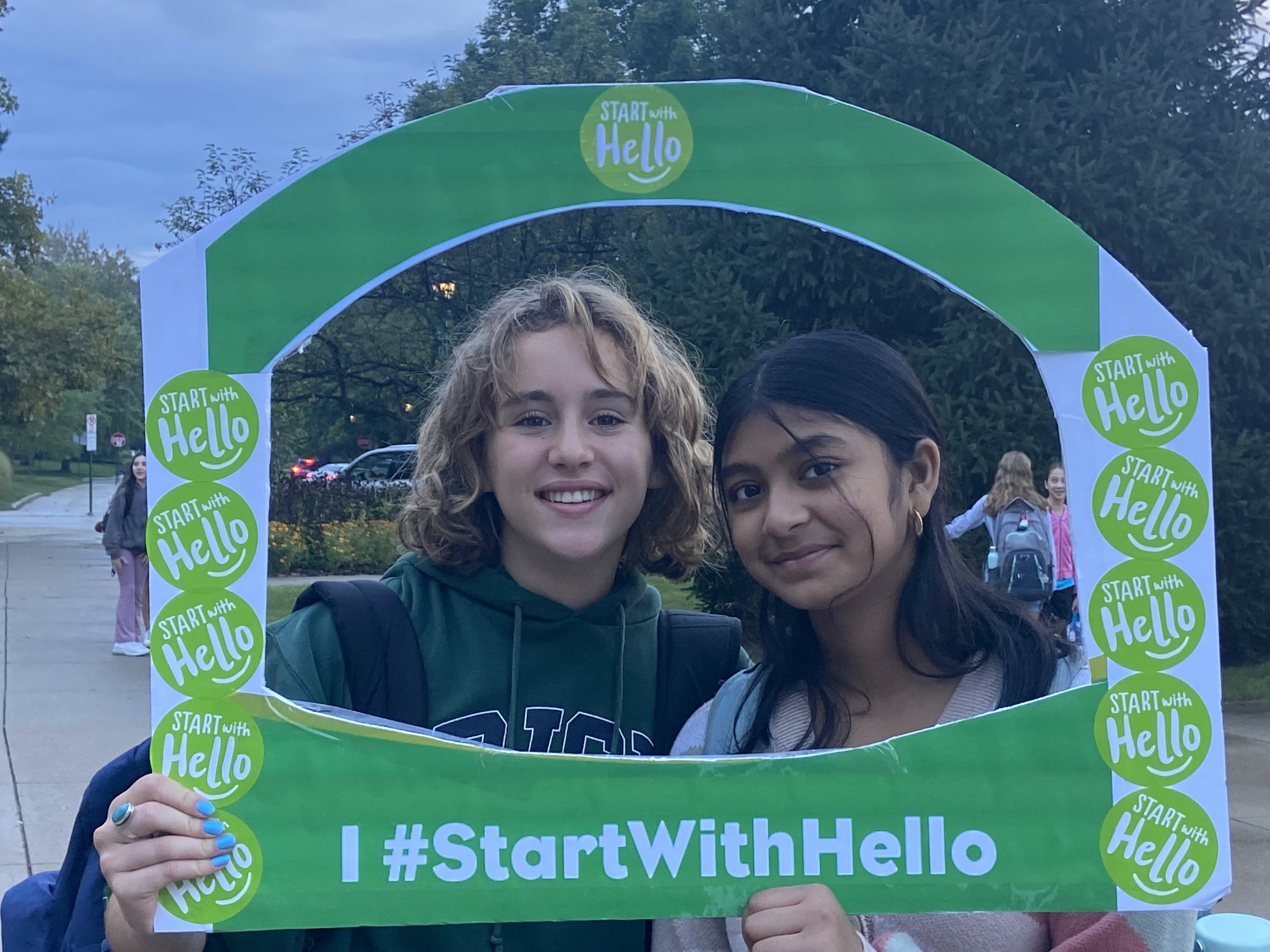 Students posing with a Start With Hello photo board
