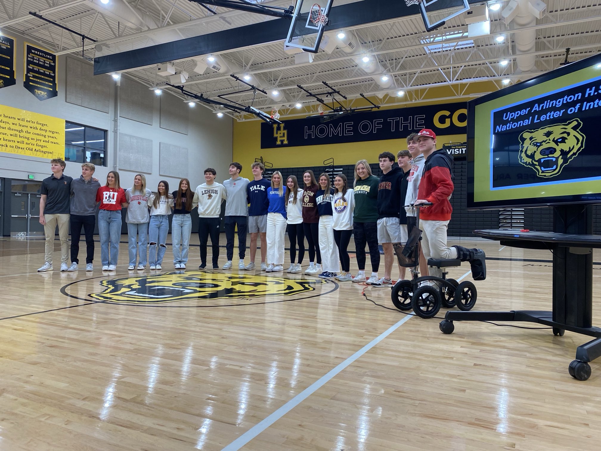 The 19 student-athletes posing arm in arm at midcourt in front of the Golden Bear logo in the Upper Arlington High School gymnasium